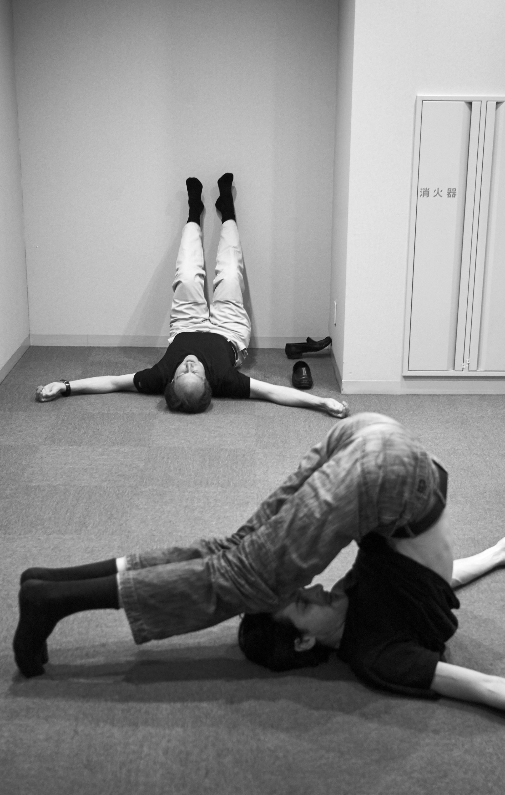  Two musians of The deutsche Kammerphilharmonie Bremen doing streching exercises on the floor before the concert in the Tokyo Opera City Concert Hall, Tokyo, Japan 16.7.2007, The deutsche Kammerphilharmonie Bremen on tour through Japan. (In Tune – Variations on an Orchestra)